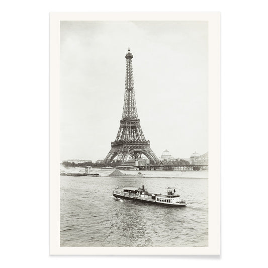Black and white photograph and poster of the Eiffel Tower in Paris with a vintage boat on the Seine river wall decor artwork, with black aluminium frame on white background