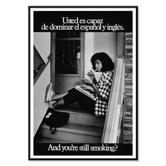Young woman reading and smoking on stairs in bilingual anti-smoking poster by US Department of Health and Human Services titled Usted es capaz de dominar el español y inglés and you are still smoking, with black aluminium frame on white background