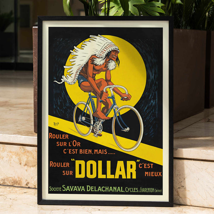 Michel Liebeaux Dollar Bicycles poster with advertising cyclist, white headdress, yellow circle, black background and bold orange lettering, framed and displayed in home decor