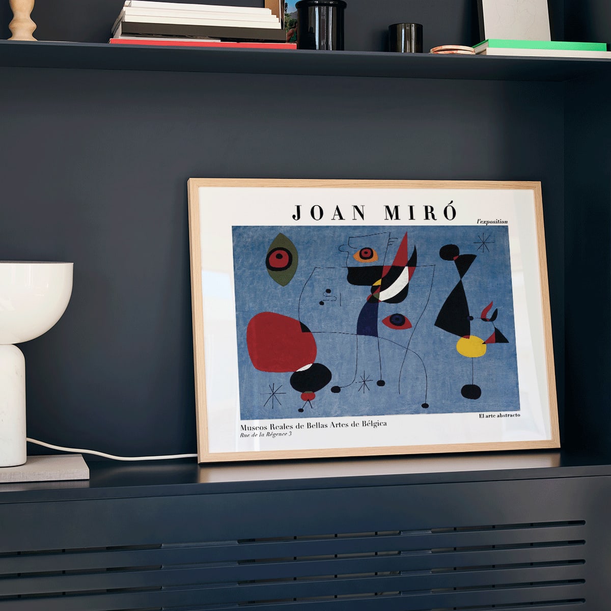 Exhibition poster of abstract artwork Woman and Bird at Night by Joan Miro with colorful shapes on a blue background, framed and displayed in modern living room decor