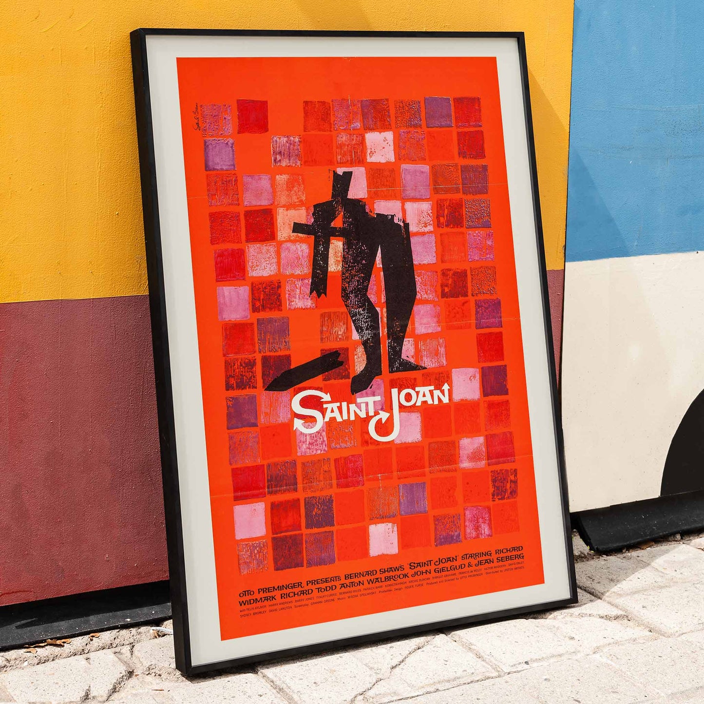 Abstract red and black Saint Joan Movie poster by Saul Bass with stylized figure on checkered background and abstract red squares, framed and displayed in home decor