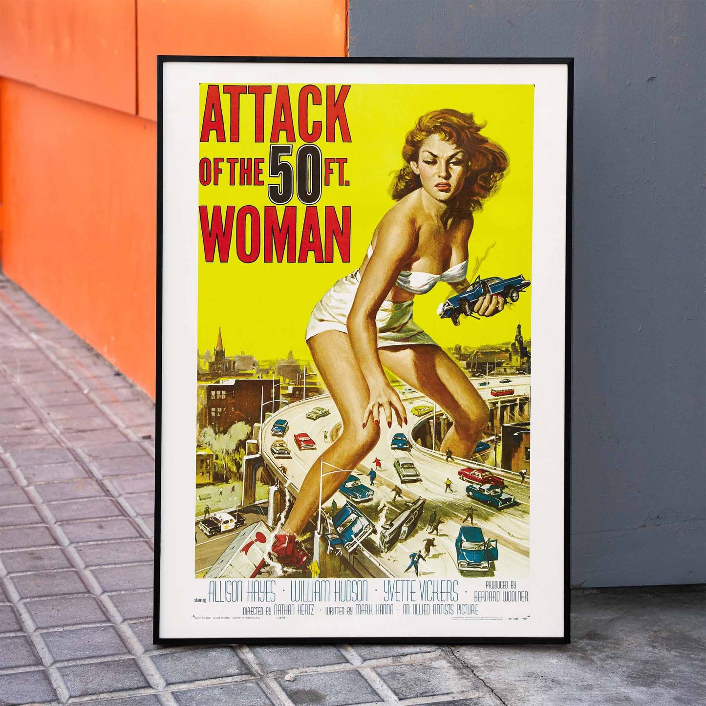 Giant woman towering over city and highway holding cars Attack of the 50ft Woman poster artwork by Reynold Brown, framed and displayed in home decor