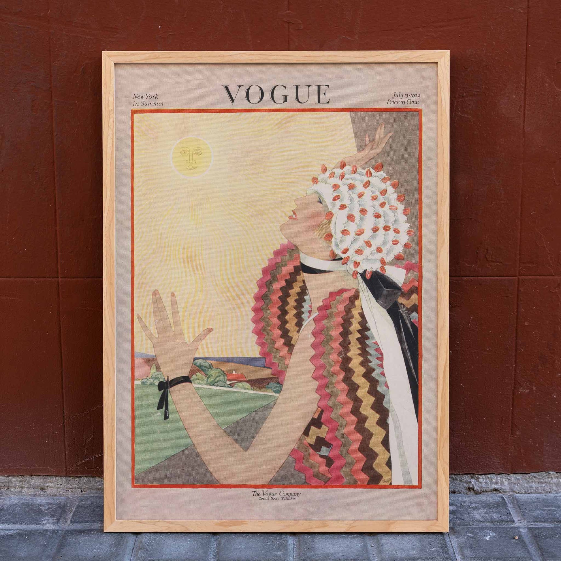 Art Deco Vogue poster of a woman in vibrant attire reaching for the sun by George Plank, framed and displayed in home decor