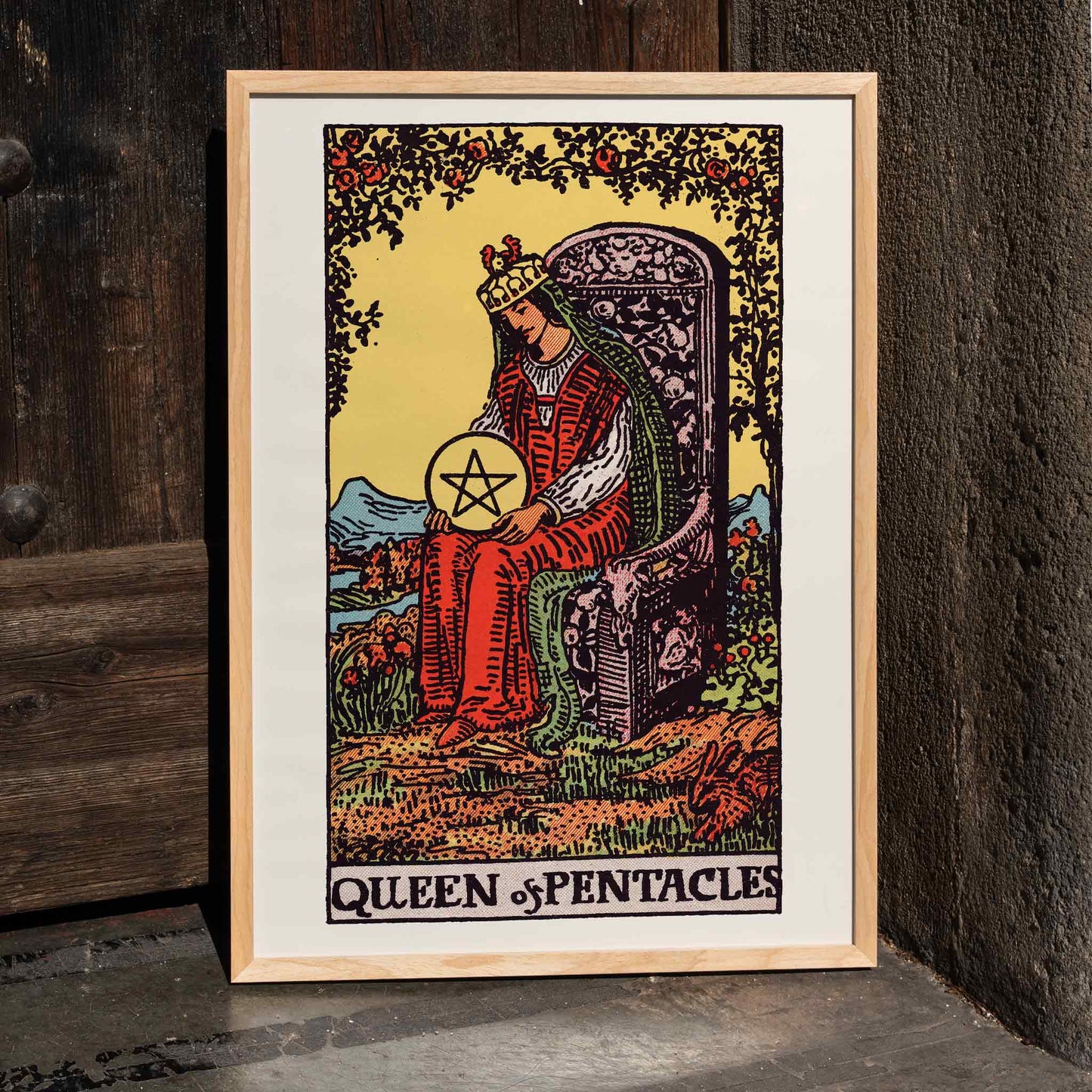 Queen of Pentacles tarot card poster by Pamela Colman Smith with crowned woman in red robes and pentacle, framed and displayed in home decor